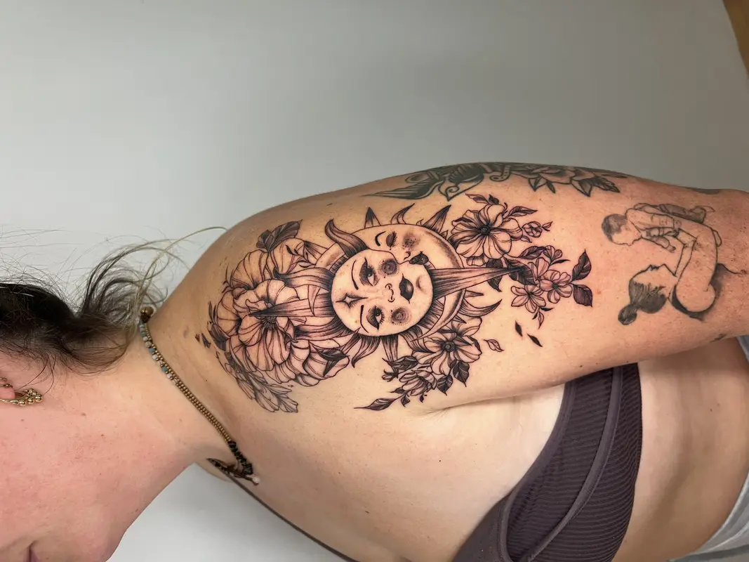 Sol con rostro humano y corona de flores en el hombro, blackwork.