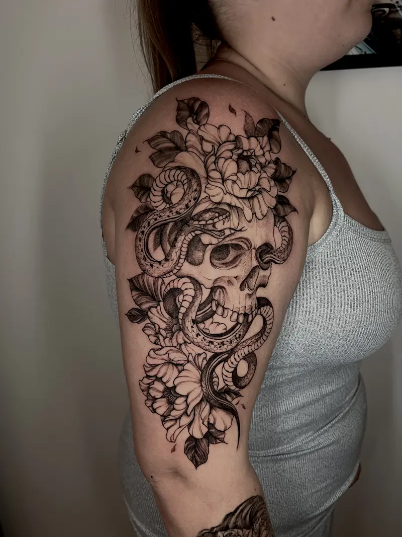 Calavera con serpiente y flores en el brazo, tinta negra.