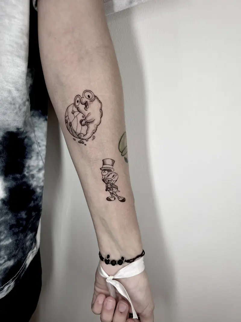 Dos mini tattoos estilo ilustración: personaje búho abrazando una bola de discoteca y un personaje pequeño con sombrero.